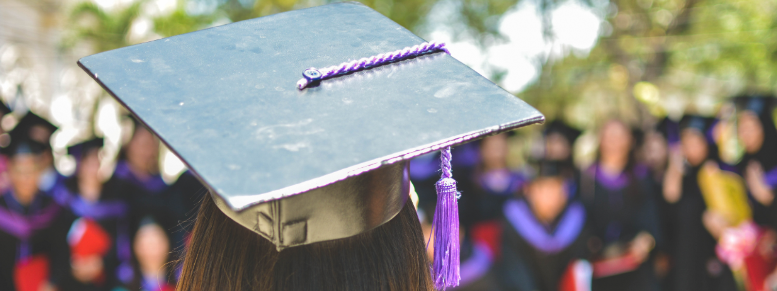 A graduate stands in front of her peers wearing a mortarboard